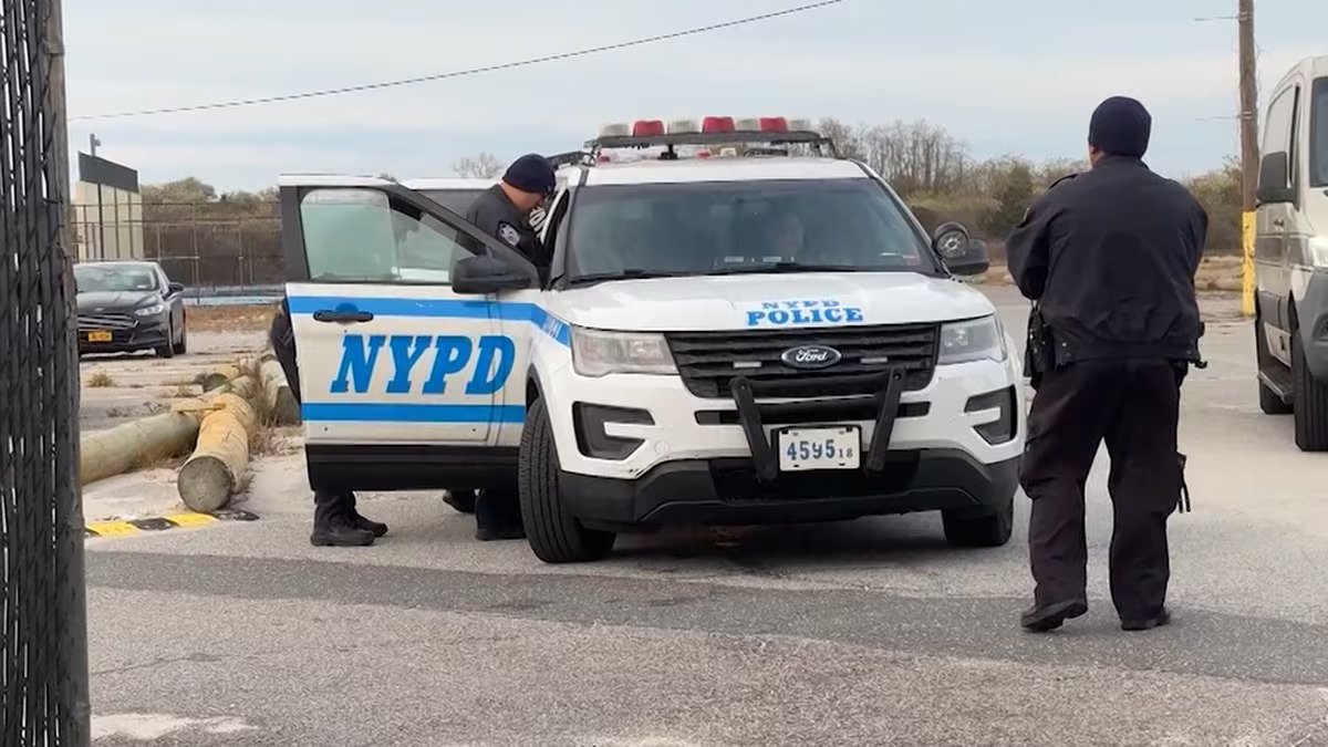 Police tape at a New York City beach with investigators in the background